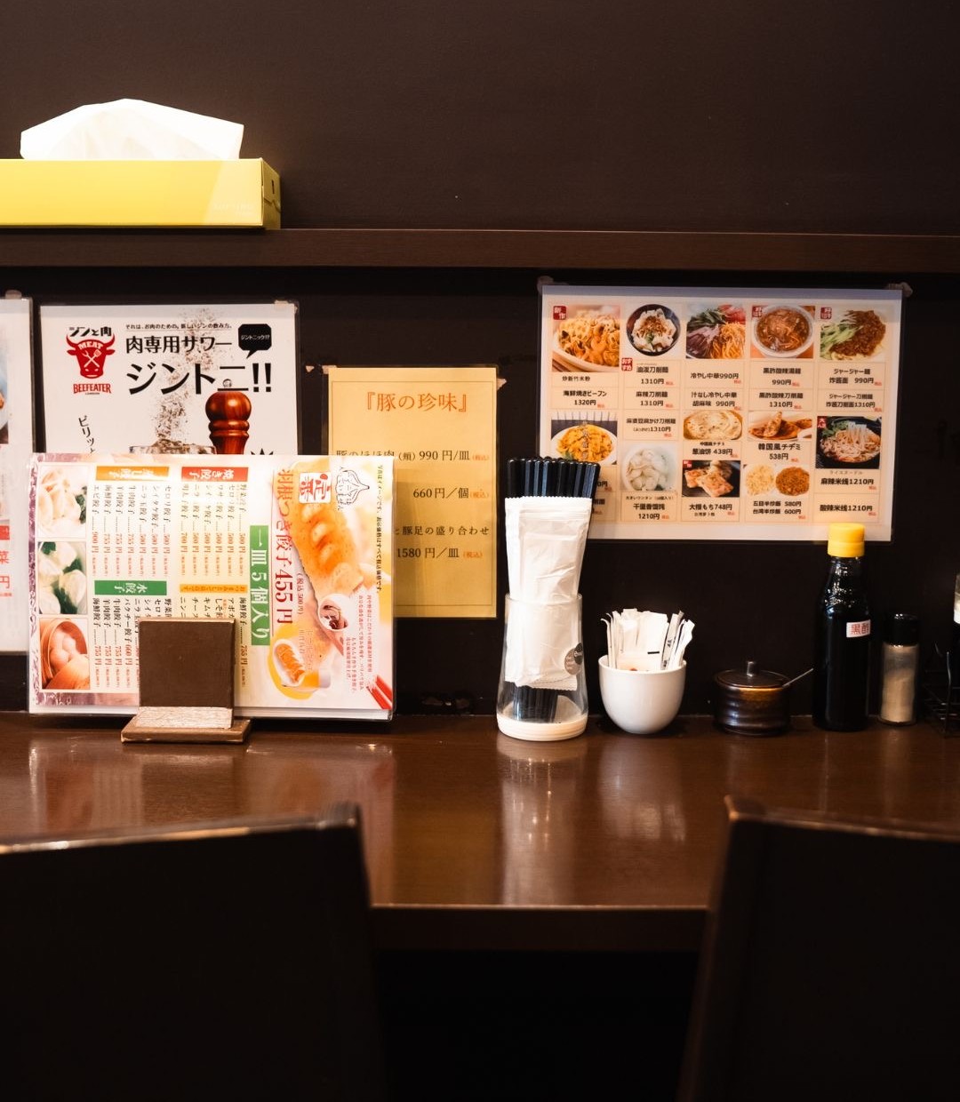 カウンターに置かれた羽根つき餃子のメニューと調味料